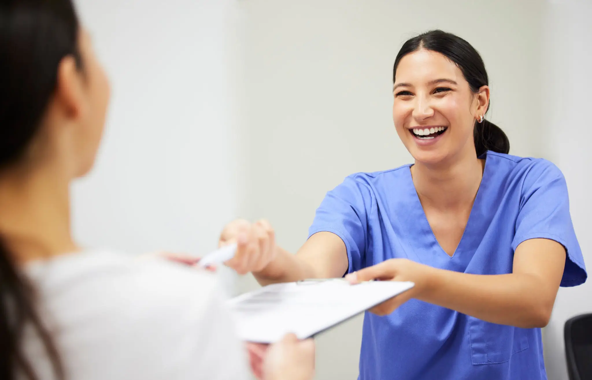 682cdfdd0a043_928bf456-383c-452a-b0c7-f1ce391c6493 A woman in scrubs is handing out papers